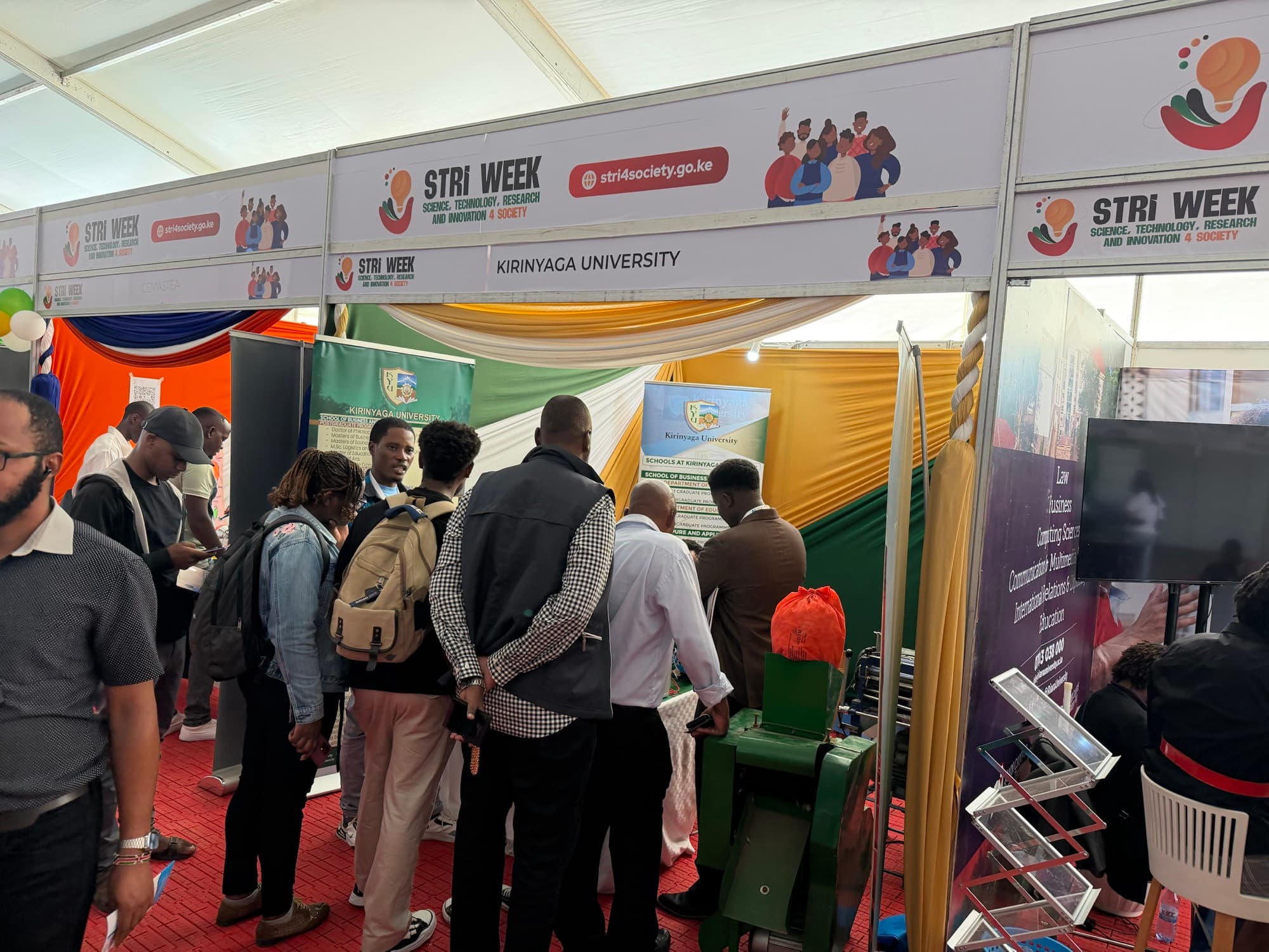 Visitors gathered at the Kirinyaga University stand at STRI Week, KICC. STRI Week banners overhead read 'Science, Technology, Research and Innovation 4 Society'.
